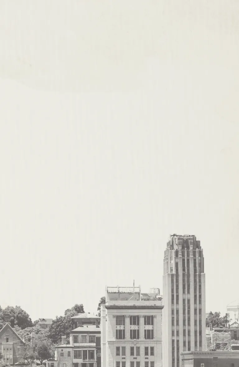 Black and white cityscape featuring historic and modern buildings under a clear sky.