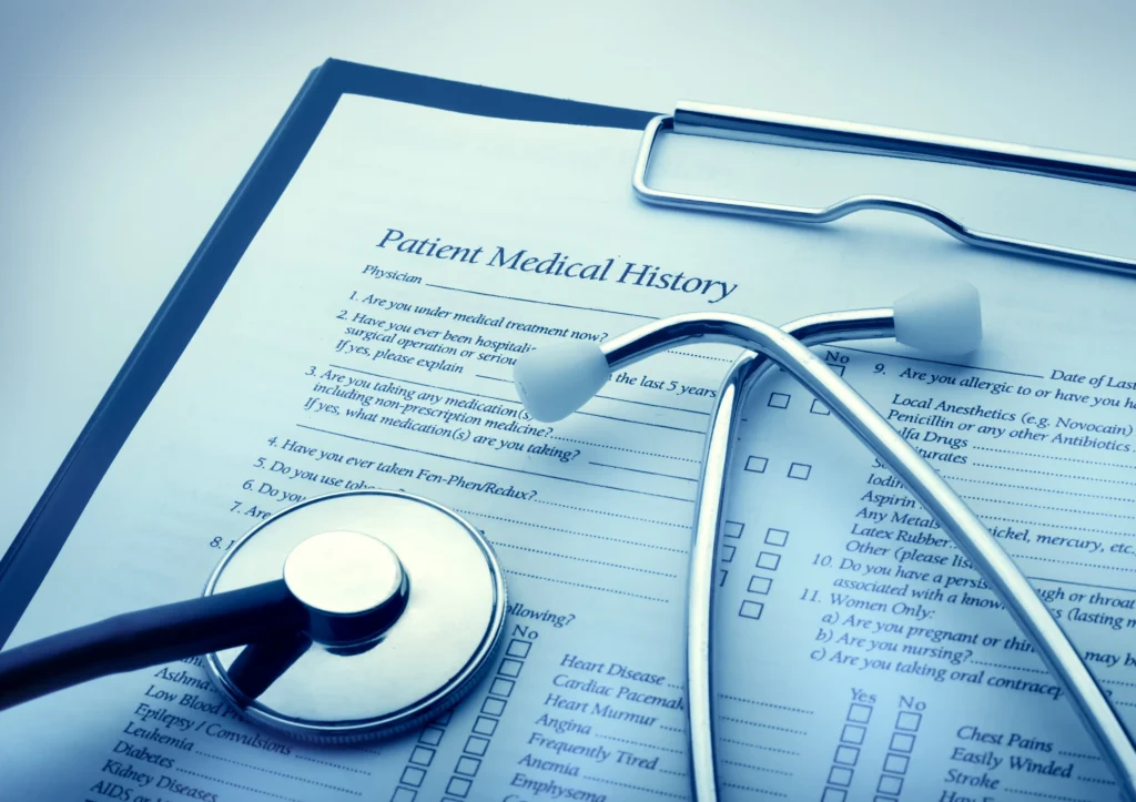 Patient medical history form on clipboard with stethoscope placed on top.