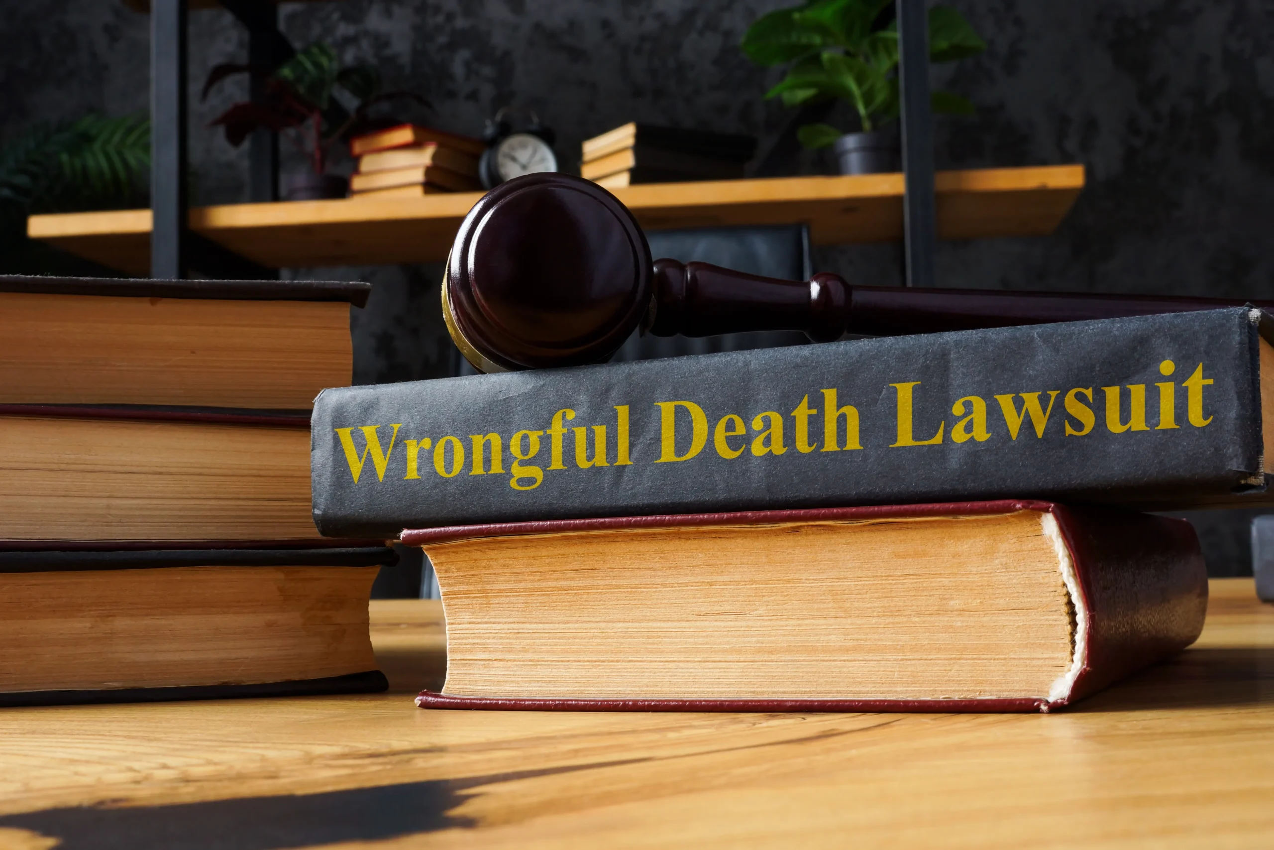 Close-up of a gavel resting on a law book titled "Wrongful Death Lawsuit" on a wooden desk.
