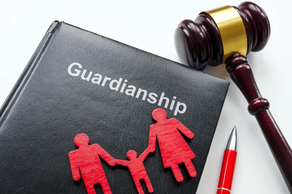 Black book titled "Guardianship" with red family figures, wooden gavel, and red pen on white surface.